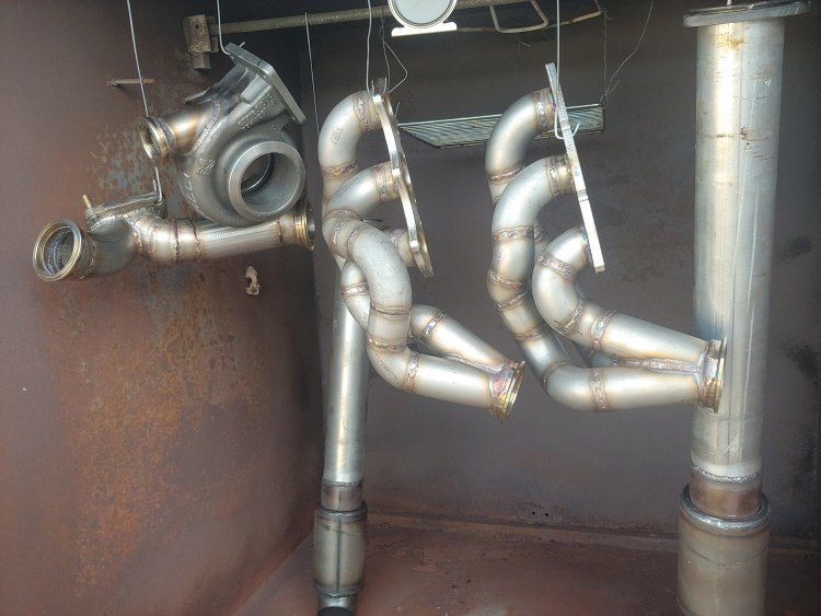 Parts hanging in a coating booth, including a turbo housing and exhaust components.